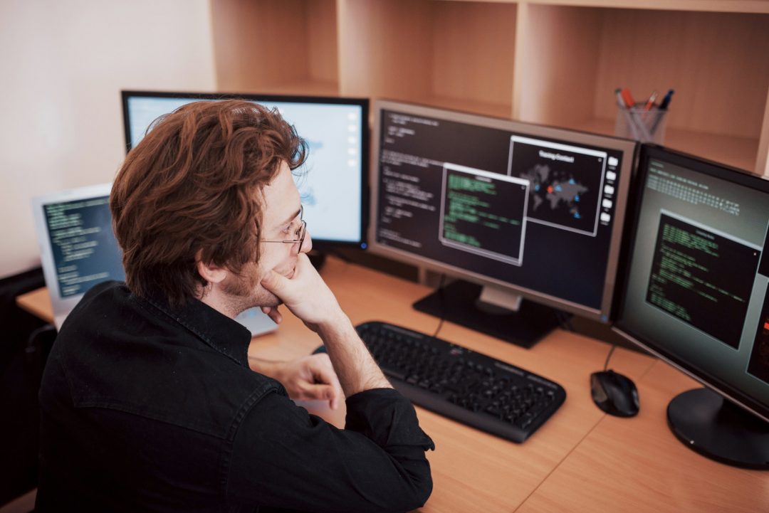 male-programmer-working-on-desktop-computer-with-many-monitors-at-office-in-software-develop-company.jpg